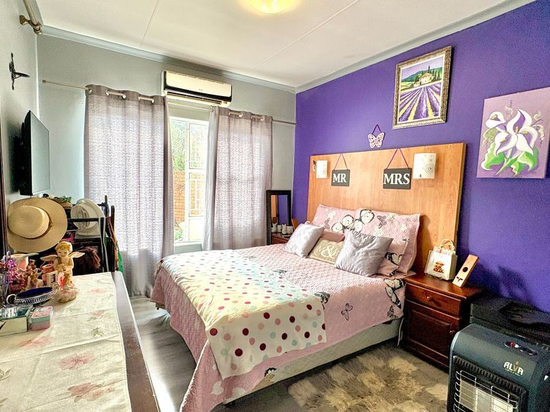 A bedroom featuring a built-in headboard and a wall-mounted split-system air conditioning unit.