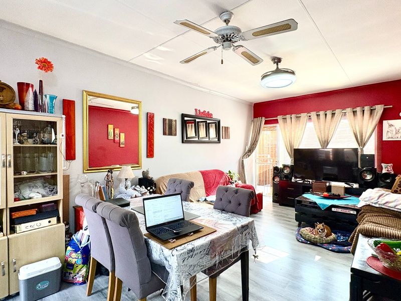 Open-plan living and dining area featuring laminate flooring, a ceiling fan, and access to an outdoor space through a sliding glass door.