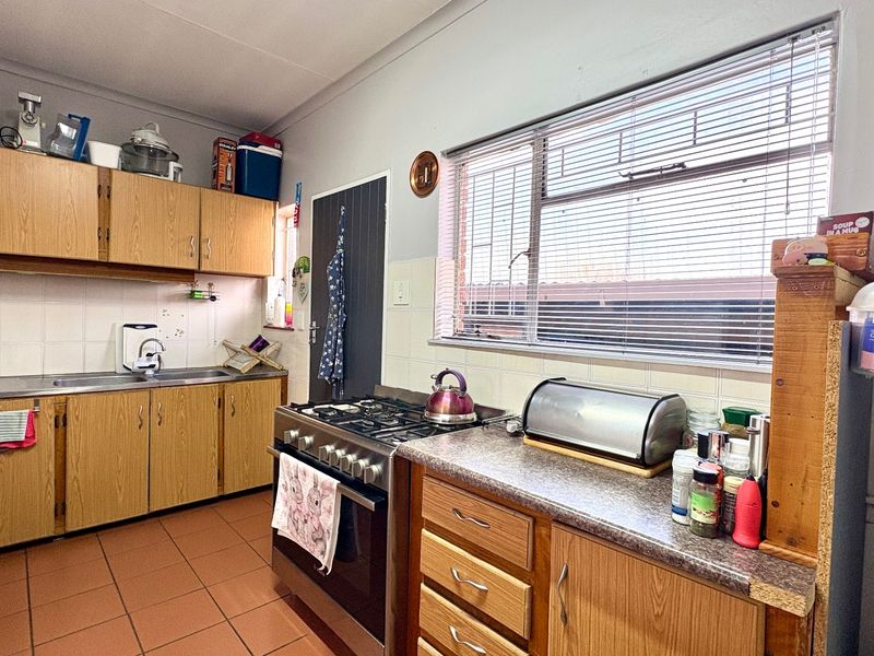 Functional kitchen featuring laminate cabinetry, gas stove, tiled backsplash, and tiled flooring, offering a practical layout with ample counter space.