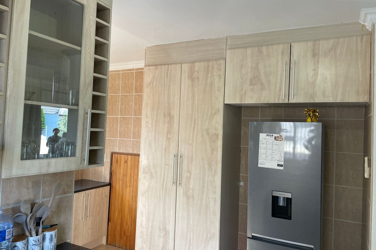 A functional kitchen featuring light wood-finish cabinetry, integrated storage, tiled backsplash, and dark countertops, offering a clean and practical workspace.