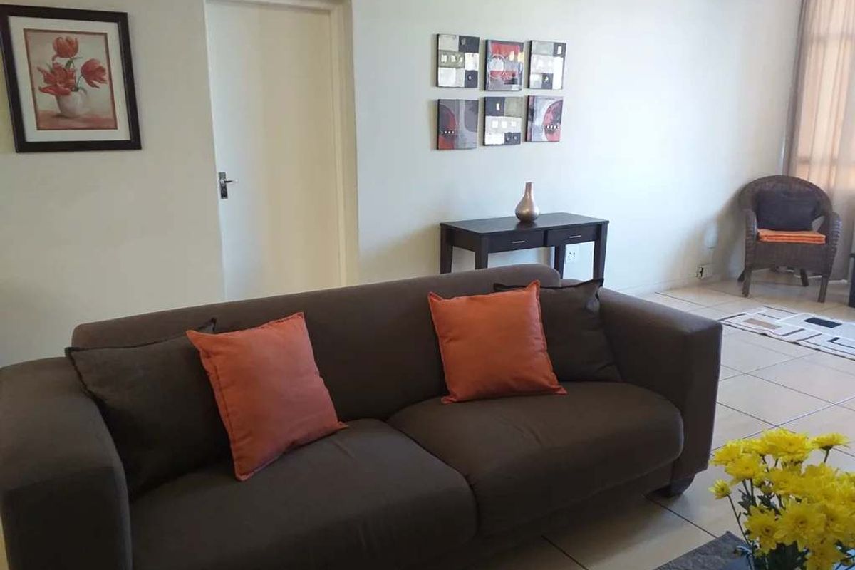 A living room area featuring neutral tiled flooring and plain walls, providing a functional and well-lit space for relaxation.
