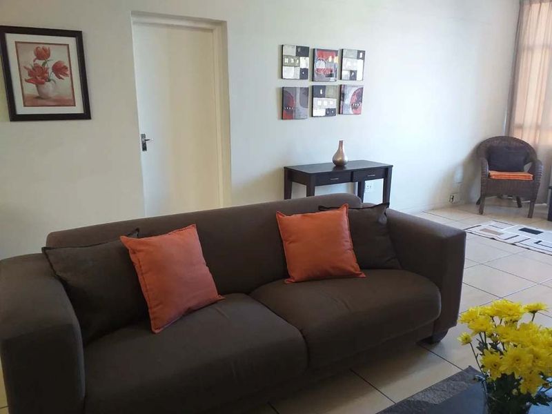 A living room area featuring neutral tiled flooring and plain walls, providing a functional and well-lit space for relaxation.