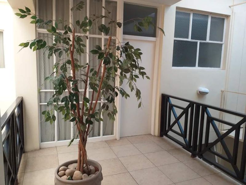 A covered balcony area featuring tiled flooring, a protective railing, and access through a multi-pane glass door.