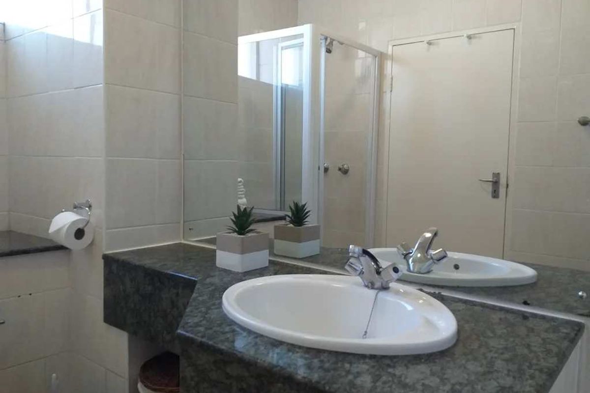 A functional bathroom featuring a stone-topped vanity with an inset basin, chrome fixtures, wall-to-wall tiling, and a separate shower enclosure.