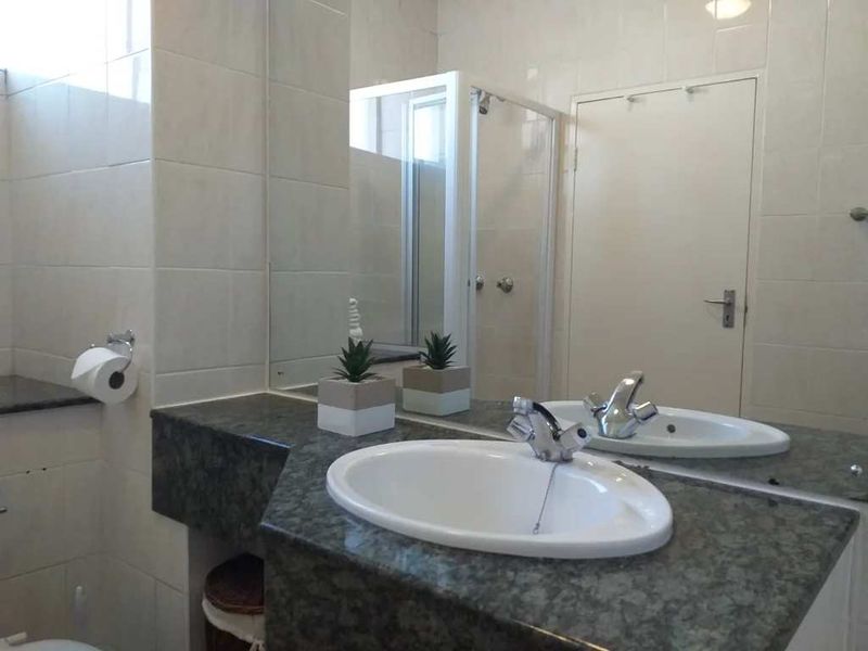 A functional bathroom featuring a stone-topped vanity with an inset basin, chrome fixtures, wall-to-wall tiling, and a separate shower enclosure.