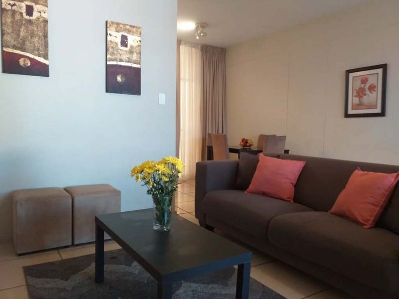 A comfortable living room area featuring tiled flooring and access to an adjacent space through a sliding glass door.