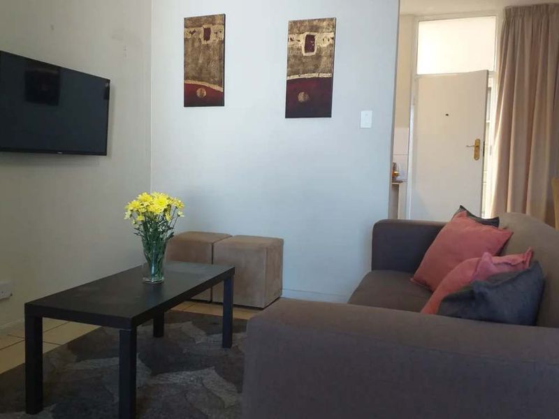 A compact living room area featuring tiled flooring and neutral wall finishes, providing a functional space for relaxation.