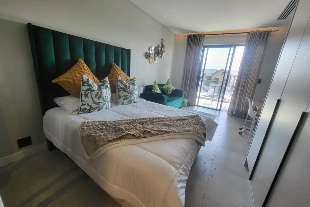 A well-maintained bedroom featuring tiled flooring, built-in wardrobes, and a sliding glass door providing access to an outdoor balcony area.