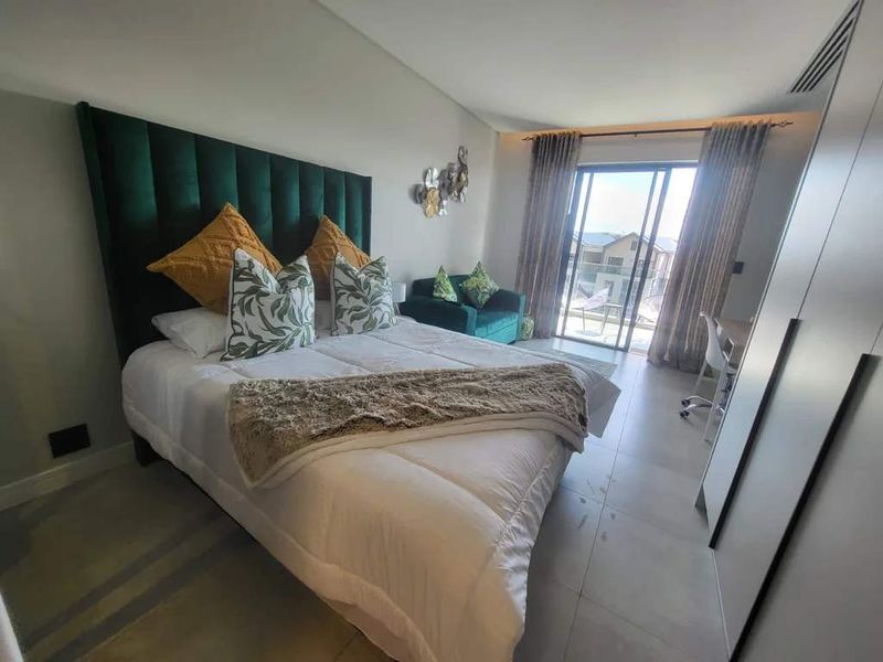 A well-maintained bedroom featuring tiled flooring, built-in wardrobes, and a sliding glass door providing access to an outdoor balcony area.