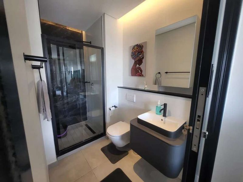 Modern bathroom featuring a walk-in shower with glass enclosure, wall-hung vanity with basin, and a wall-hung toilet with concealed cistern.