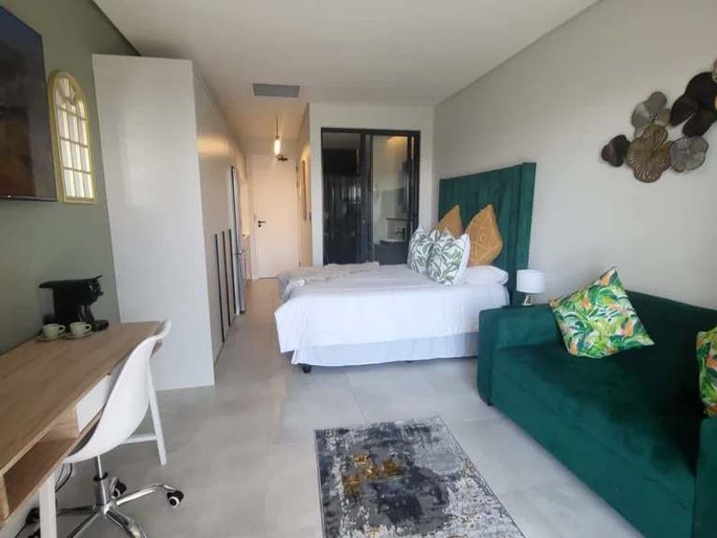 Modern studio bedroom featuring tiled flooring, built-in cupboards, and ducted air conditioning with access to an adjoining space through a glass door.