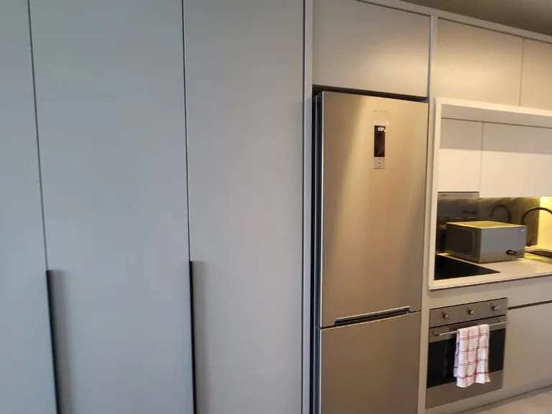 Modern kitchen featuring sleek built-in cabinetry, stainless steel appliances, integrated oven, and a clean, minimalist design with under-cabinet lighting.