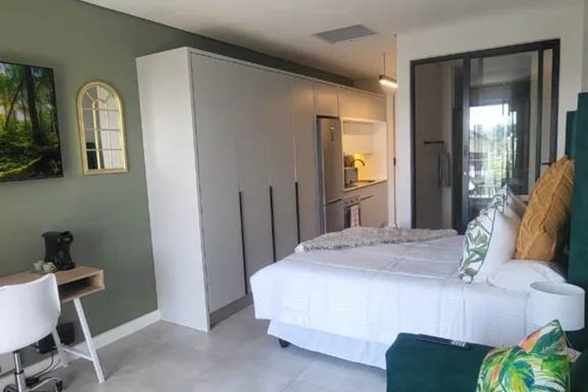 Modern open-plan studio apartment featuring sleek built-in cabinetry, tiled flooring, and seamless access to a private balcony through sliding glass doors.