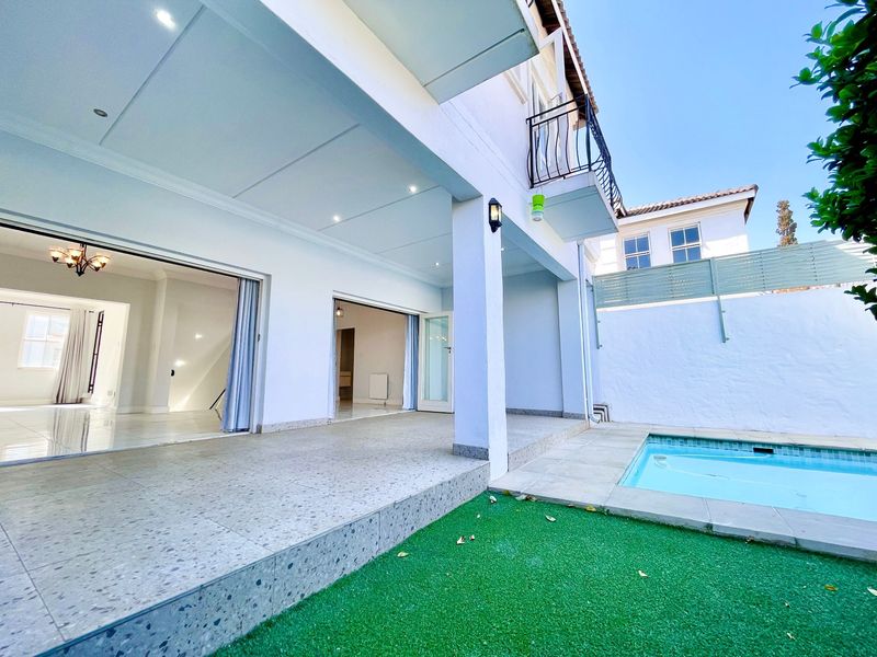 Covered patio area featuring terrazzo flooring and recessed lighting, seamlessly connecting to the interior living space and overlooking the swimming pool and garden.