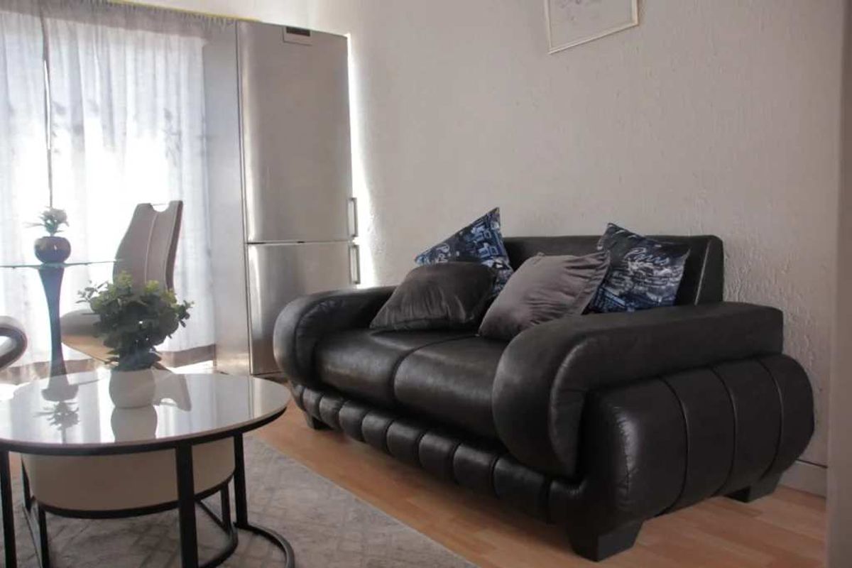 A living room area featuring laminate flooring and neutral wall finishes, providing a functional space for relaxation.