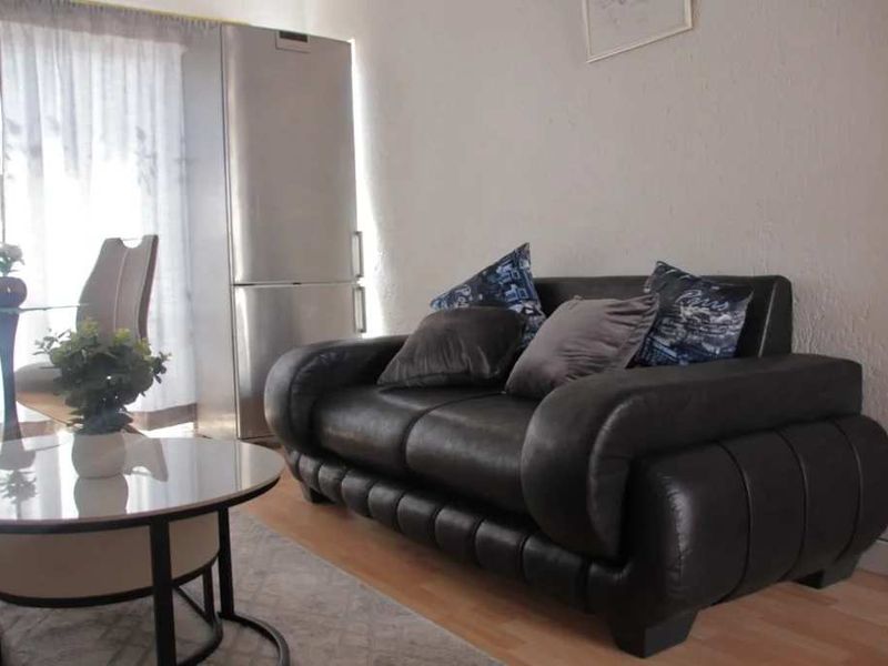 A living room area featuring laminate flooring and neutral wall finishes, providing a functional space for relaxation.