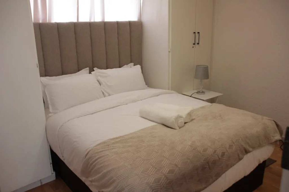 A functional bedroom featuring a built-in wardrobe and neutral finishes, providing a comfortable and practical sleeping space.