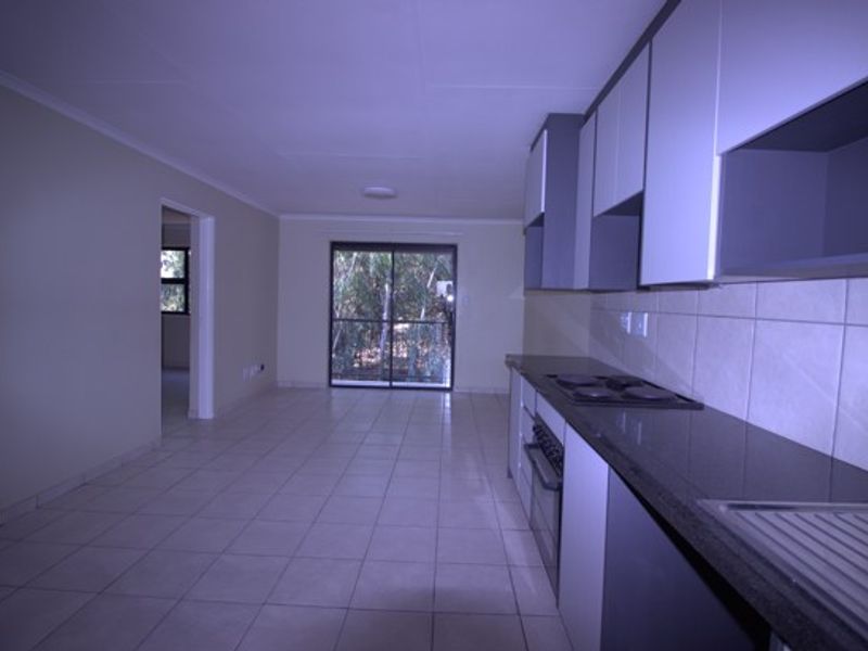 Open-plan kitchen and living area featuring tiled floors, built-in cabinetry with granite countertops, and a sliding door leading to the exterior.