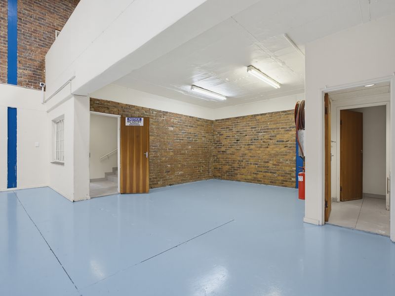 A clean, industrial utility space featuring exposed brick walls, durable epoxy flooring, and functional fluorescent lighting, suitable for storage or workshop use.