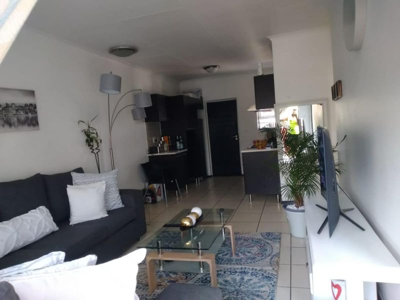 Open-plan living area featuring tiled flooring and a compact kitchen with built-in cabinetry and an extractor fan.