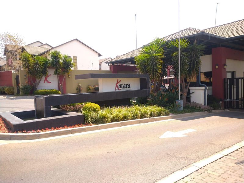 The main entrance and security gate of the Katara residential complex, featuring modern signage, a water feature, and well-maintained landscaping.