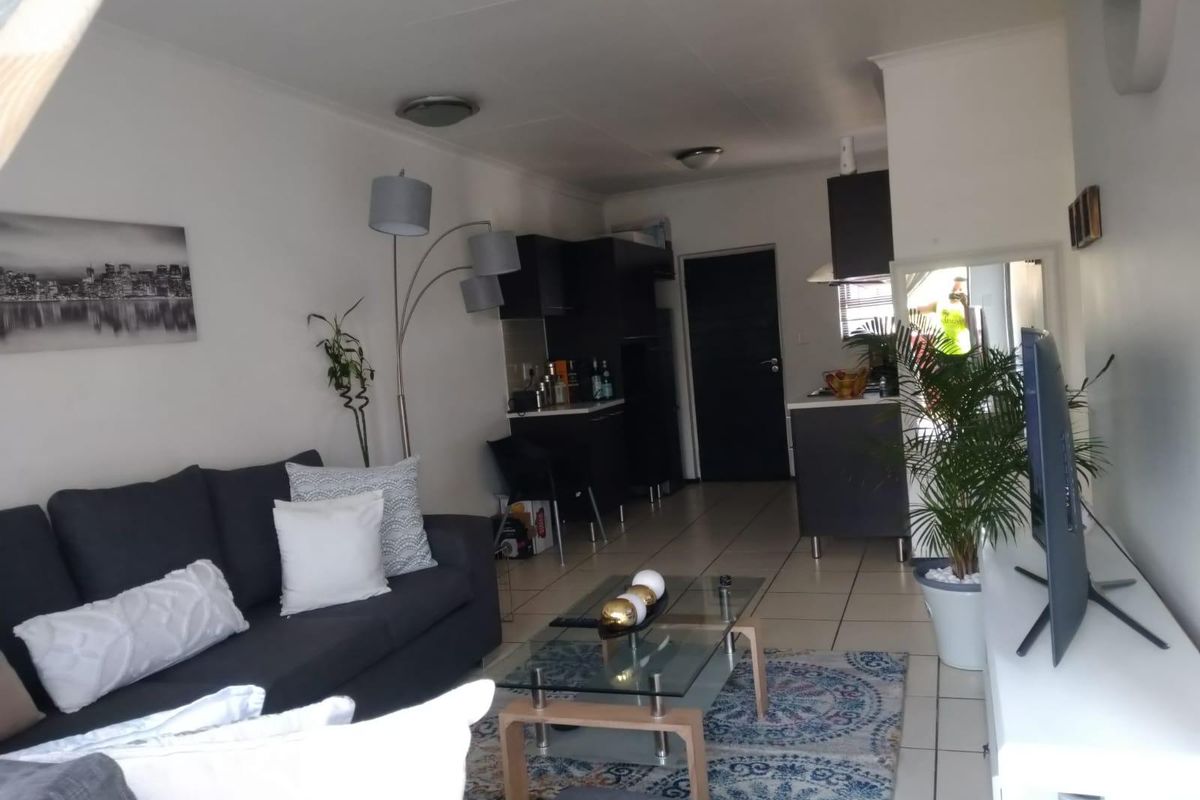Open-plan living area featuring tiled flooring and a compact kitchen with dark cabinetry and integrated extractor fan.
