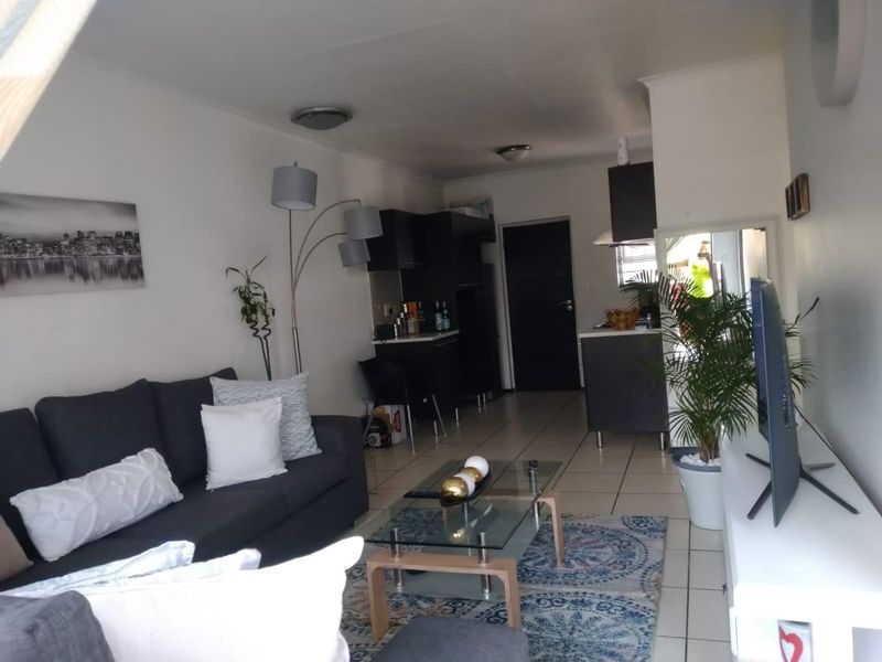 Open-plan living area featuring tiled flooring and a compact kitchen with dark cabinetry and integrated extractor fan.