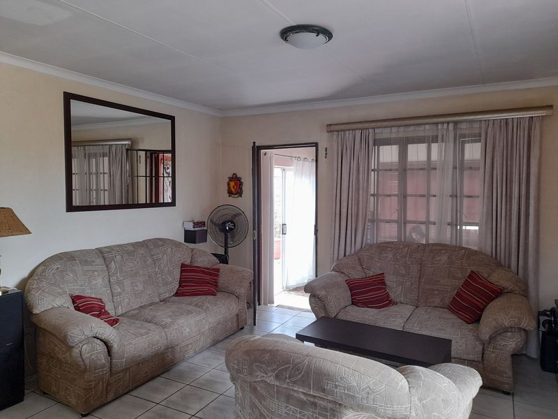 A living room featuring tiled flooring, coved ceilings, and a sliding door providing access to an outdoor area.