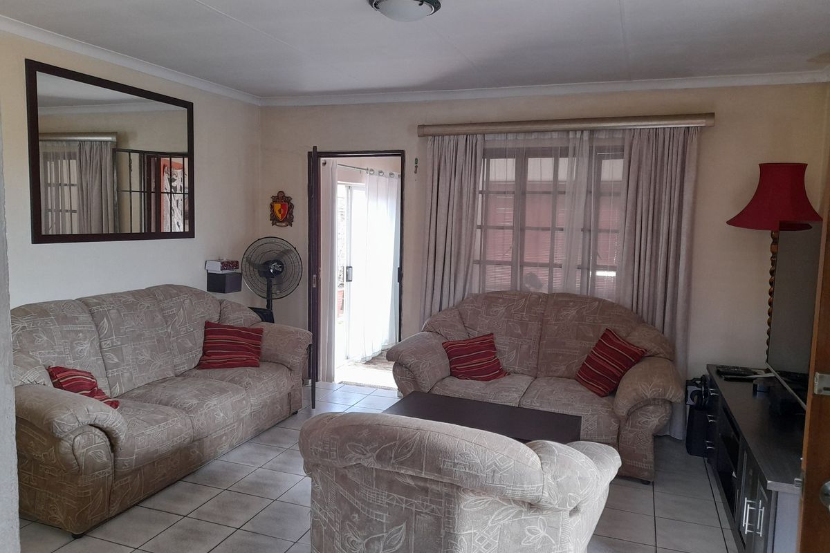 A comfortable living room featuring tiled flooring, neutral wall tones, and direct access to an outdoor area through a sliding door.