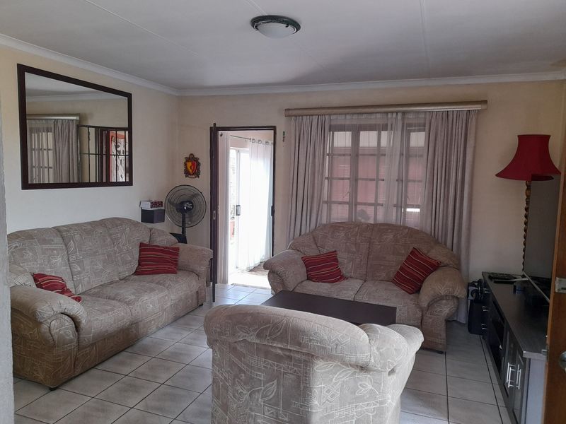 A comfortable living room featuring tiled flooring, neutral wall tones, and direct access to an outdoor area through a sliding door.