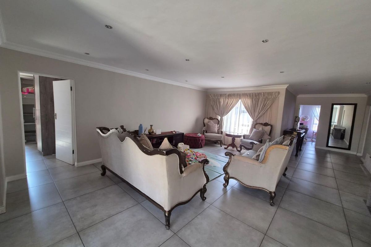 Spacious living room featuring large format floor tiles, recessed downlighting, and coved ceiling cornices, offering a neutral and well-maintained living space.