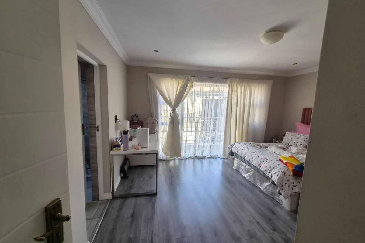 A well-lit bedroom featuring modern laminate flooring, recessed ceiling lights, and a sliding glass door providing access to an outdoor area.