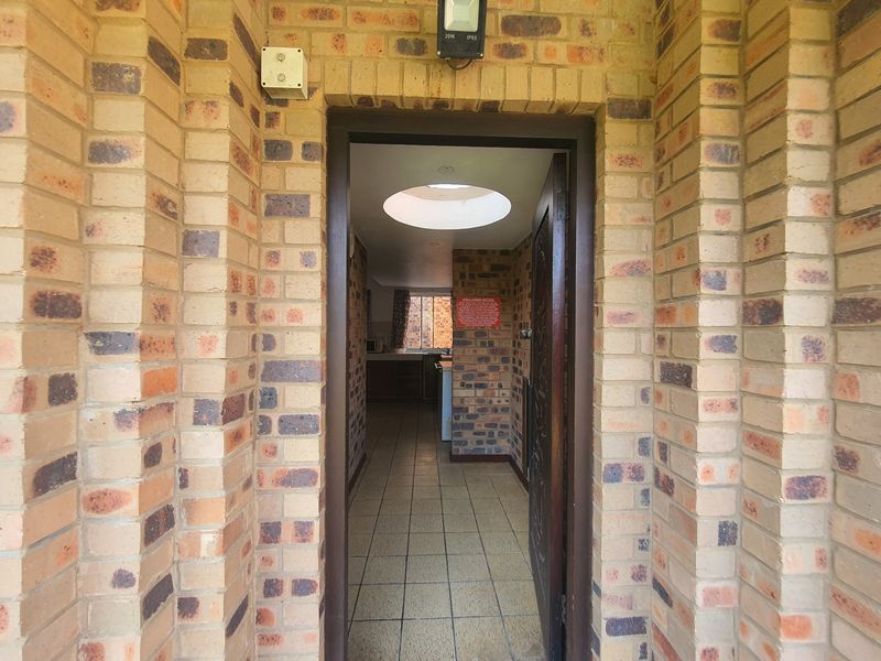 Entrance area featuring exposed brickwork, tiled flooring, and a circular skylight, providing a clear view into the interior living space.