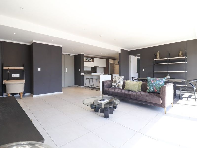 Spacious open-plan living area featuring modern tiled floors, recessed lighting, and a sleek integrated kitchen with a central island.