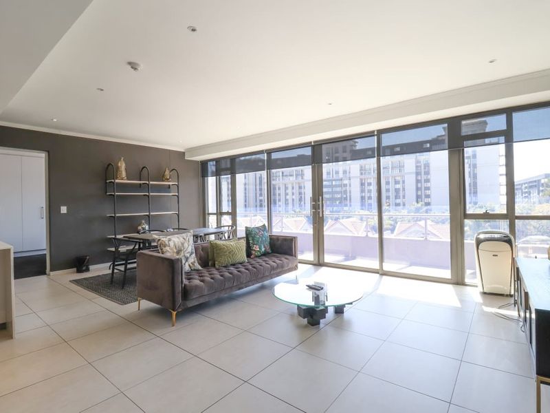 Spacious open-plan living area featuring large sliding glass doors, neutral tiled flooring, and recessed lighting, offering a bright and modern atmosphere.