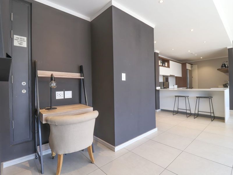 Modern open-plan living area featuring a sleek kitchen with a breakfast island, tiled flooring, and recessed lighting, creating a bright and functional space.