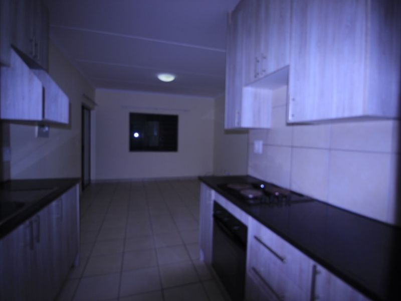 Open plan kitchen and living area featuring built-in cabinetry, integrated oven and hob, and tiled flooring throughout.