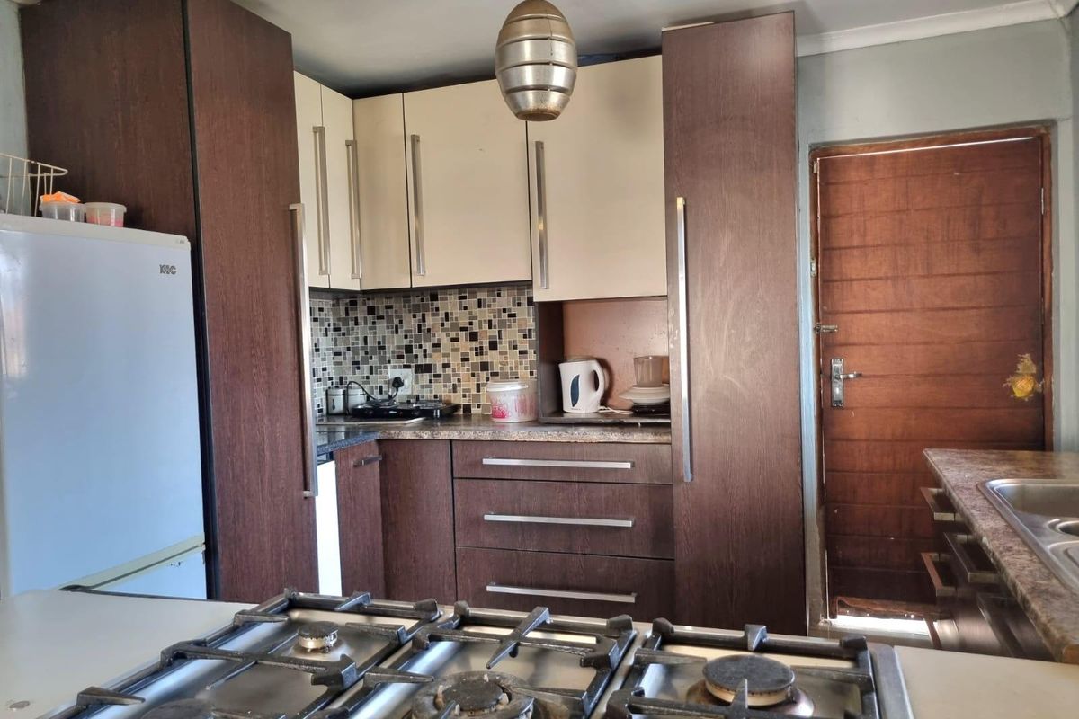 Compact kitchen featuring two-tone cabinetry, mosaic tile backsplash, gas hob, and laminate countertops with a functional layout.