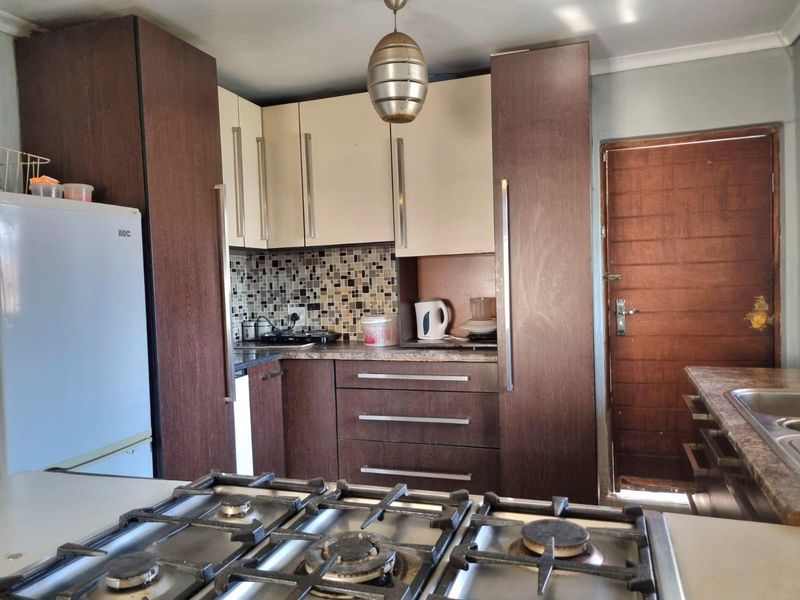 Compact kitchen featuring two-tone cabinetry, mosaic tile backsplash, gas hob, and laminate countertops with a functional layout.