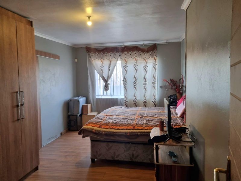 A bedroom featuring laminate flooring, a built-in wardrobe, and security bars on the window.
