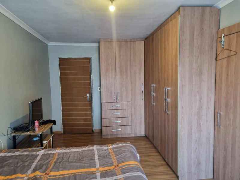 A bedroom featuring wood-look laminate flooring and extensive built-in cabinetry providing ample storage space.