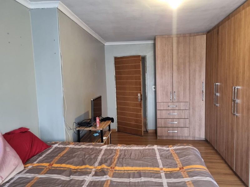 A bedroom featuring laminate flooring and extensive built-in wooden cupboards, providing ample storage space.