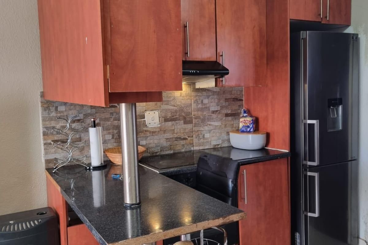 Compact kitchen featuring wood-finish cabinetry, granite countertops, a breakfast bar, and a decorative ceiling, providing a functional and efficient cooking space.