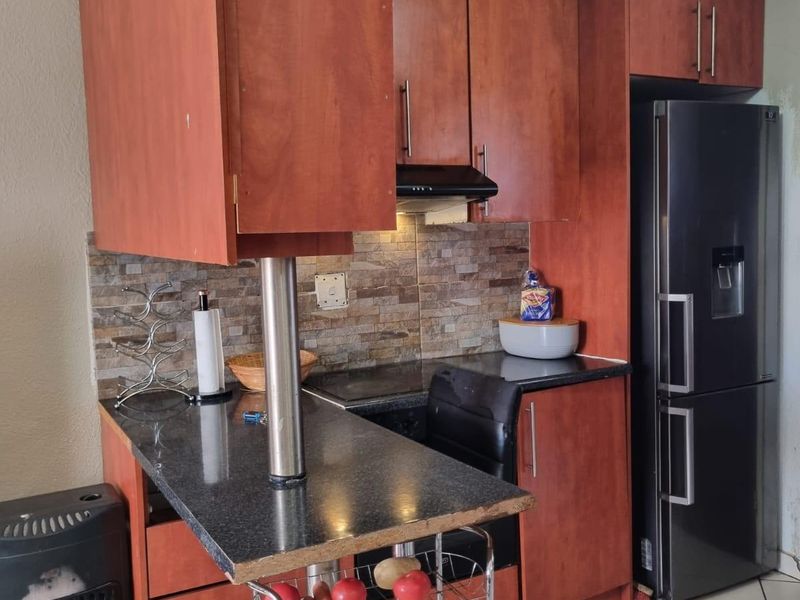 Compact kitchen featuring wood-finish cabinetry, granite countertops, a breakfast bar, and a decorative ceiling, providing a functional and efficient cooking space.