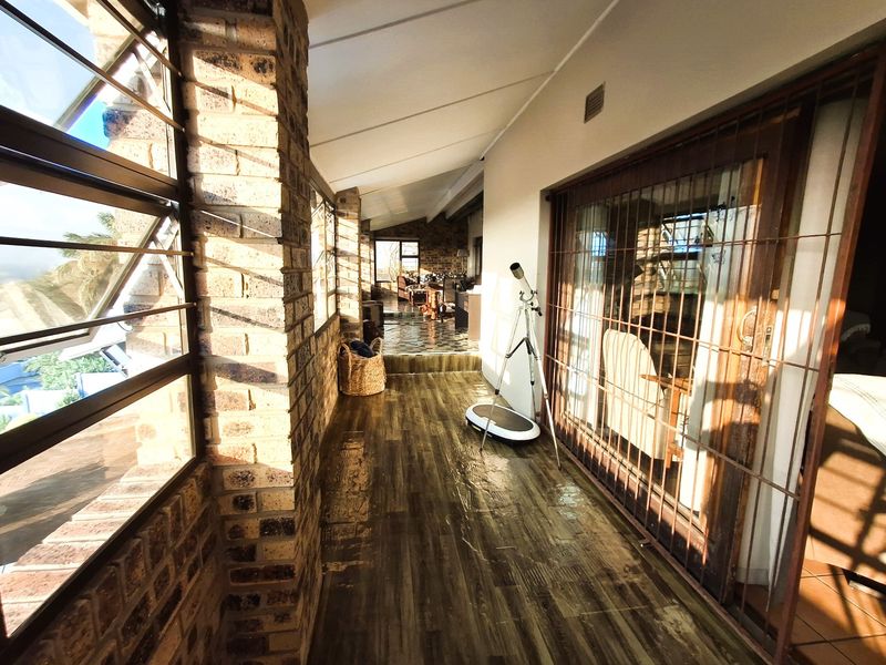 A covered patio area featuring exposed brick walls, louvered windows, and wood-look flooring, providing a transition space between the interior and exterior.