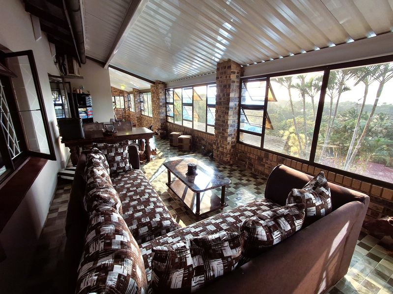 Enclosed patio area featuring exposed brick pillars, tiled flooring, and expansive windows offering natural light and garden views.