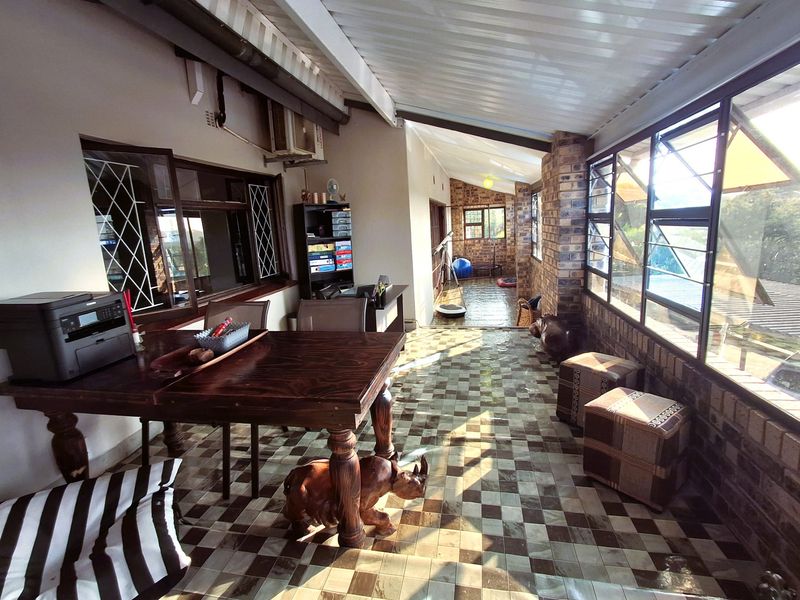 A spacious enclosed patio featuring exposed brick walls, tiled flooring, and large windows, offering a versatile space for relaxation or entertaining.