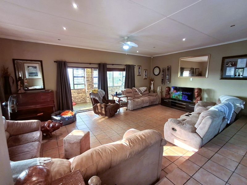 Spacious living room featuring tiled flooring, recessed lighting, a ceiling fan, and large sliding glass doors providing access to the outdoor patio area.