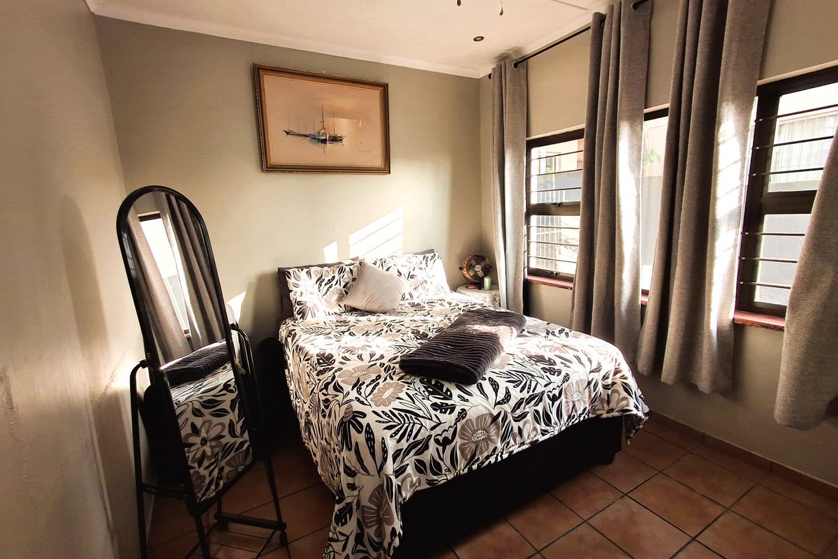 A cozy bedroom featuring tiled flooring, recessed lighting, a ceiling fan, and windows fitted with security bars.