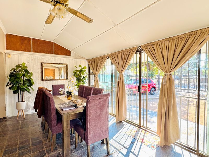Enclosed patio area featuring tiled flooring, ceiling fan, and sliding glass doors with security gates, providing a versatile space for dining or relaxation.